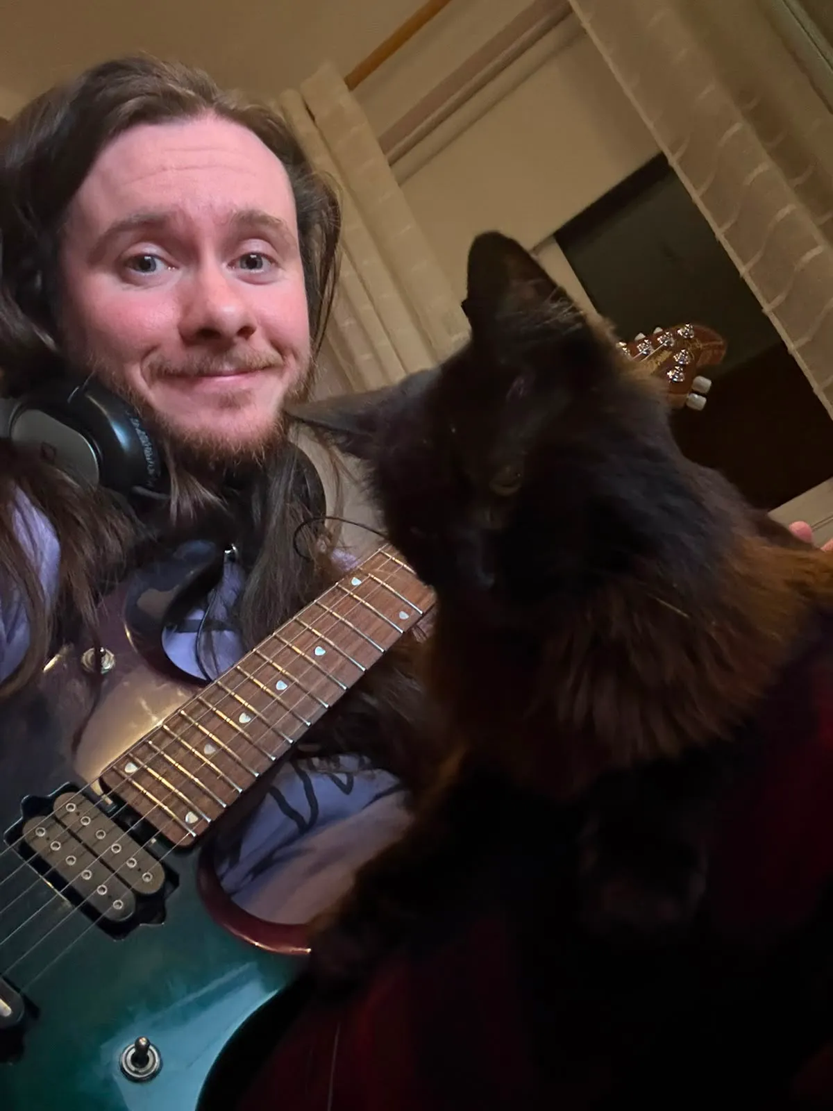 Jamie relaxing at home with his guitar and cat